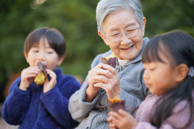 焼き芋を食べる祖母と孫二人。