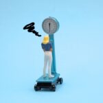 体重計に乗って困惑している女性のフィギュア