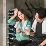 スポーツドリンクを飲みながら汗をふく男女