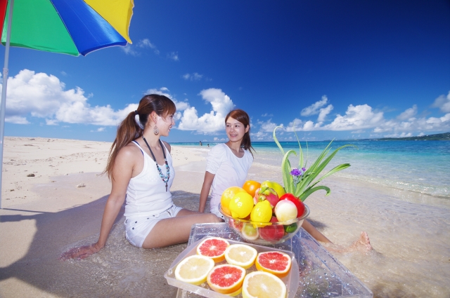 フルーツを海辺で楽しむ女性たち